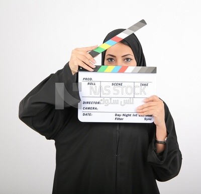 A woman with a hijab holding a clapperboard