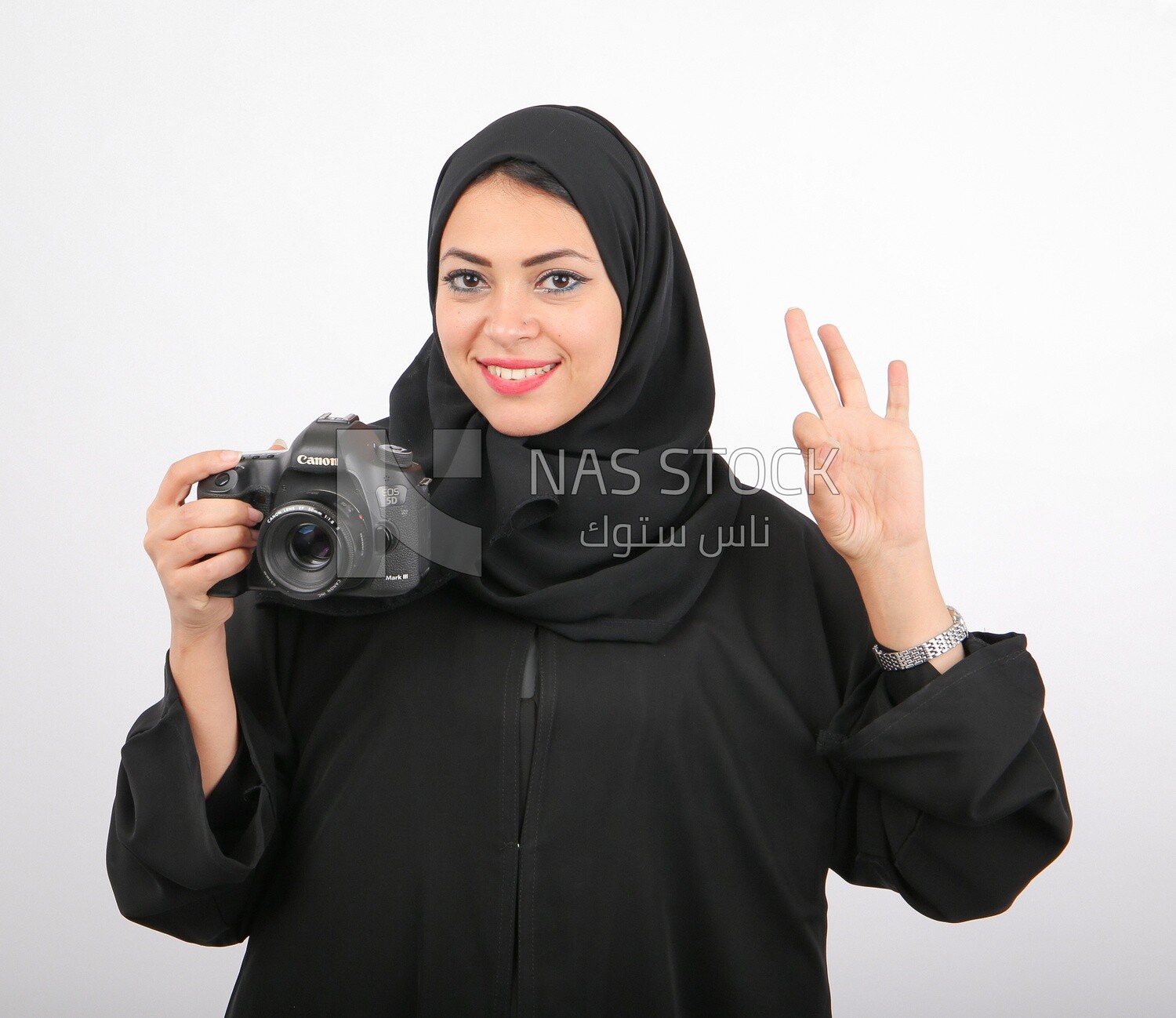 A woman with a hijab holding a camera