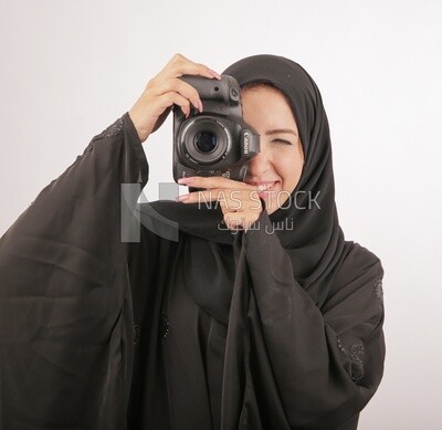 A woman with a hijab holding a camera