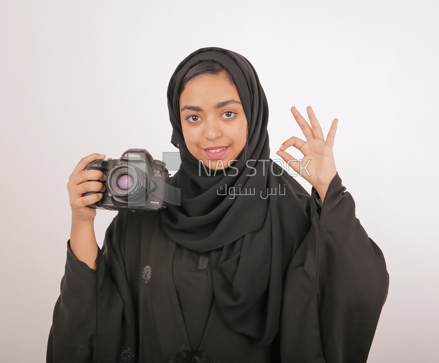 A woman with a hijab holding a camera