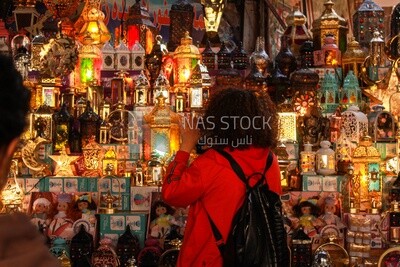 young man with curly hair is filming and documenting the moments of Ramadan celebration and Ramadan decorations in the streets of Egypt