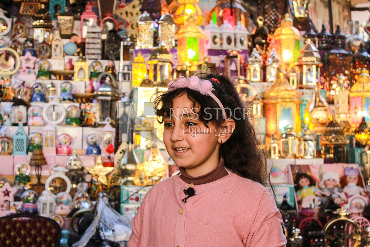 little girl stands in the middle of the lanterns happily celebrating Ramadan