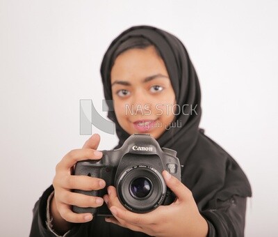 A woman with a hijab holding a camera