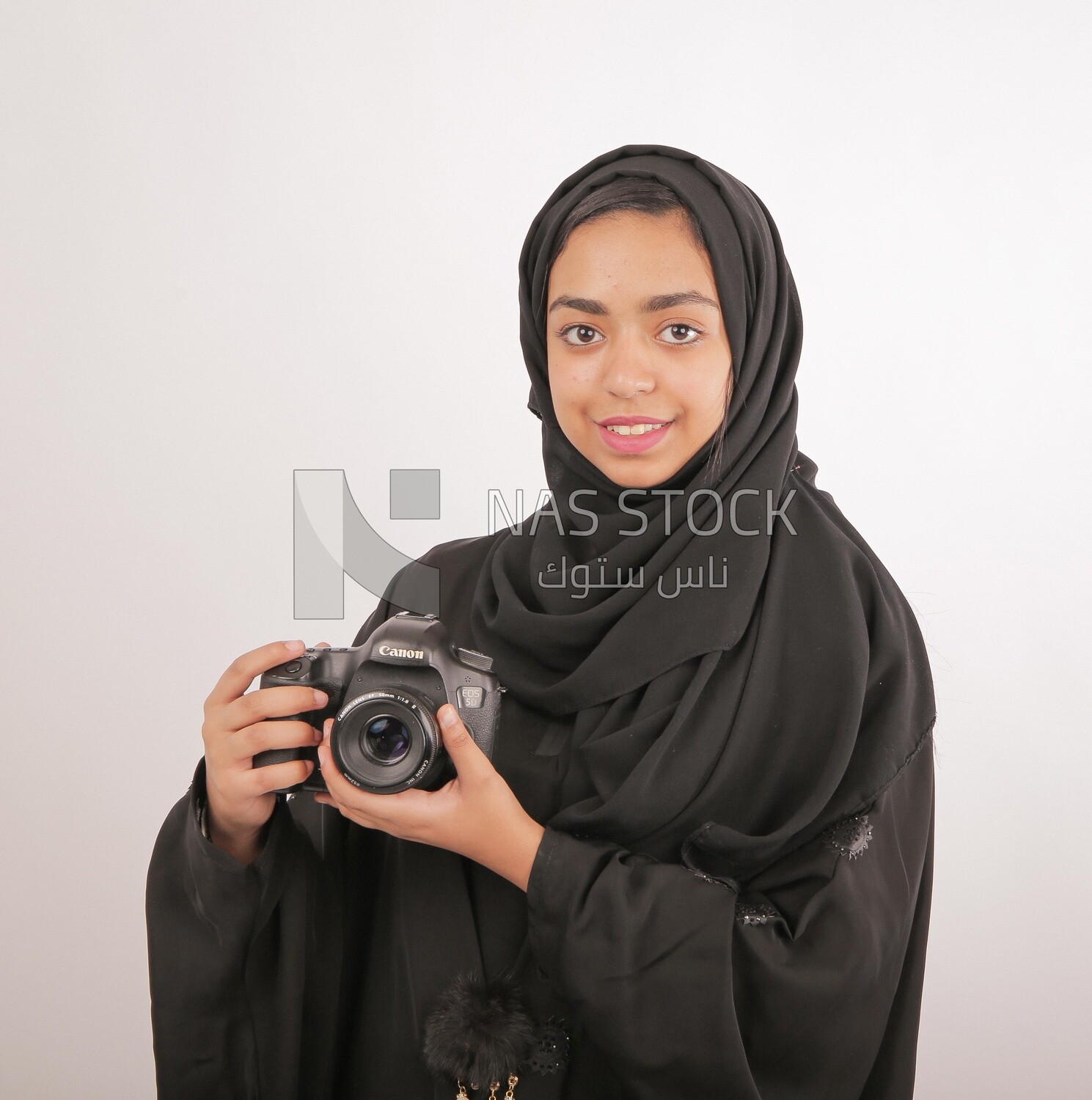 A woman with a hijab holding a camera