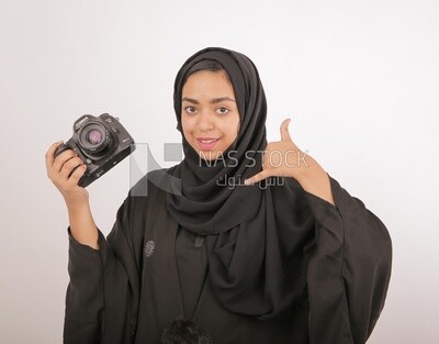 A woman with a hijab holding a camera