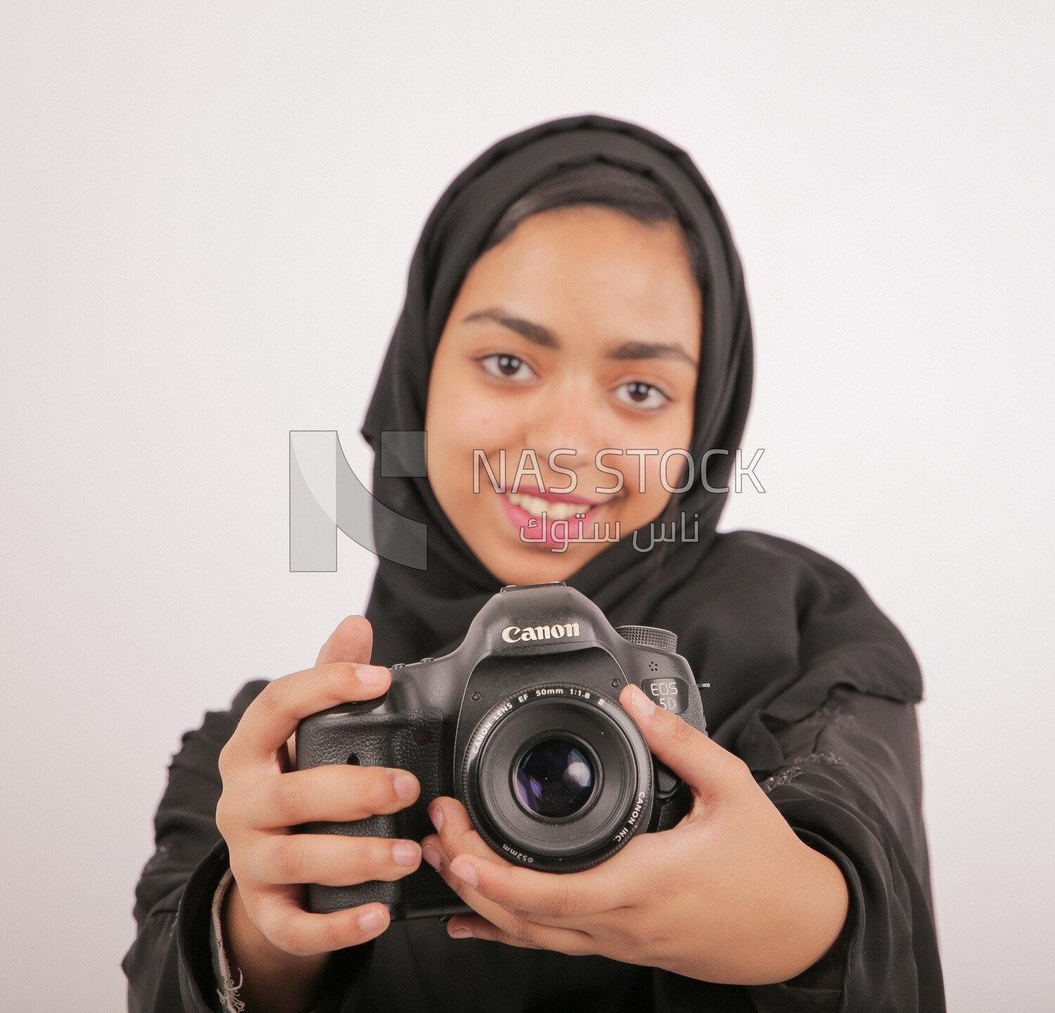 A woman with a hijab holding a camera