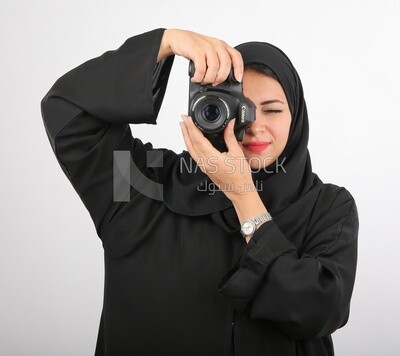 A woman with a hijab holding a camera