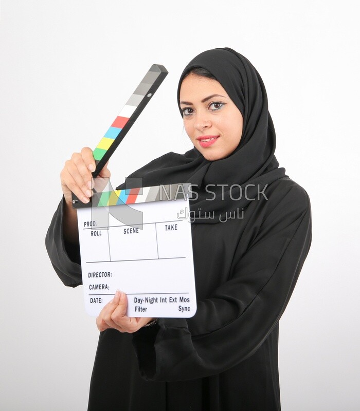 A woman with a hijab holding a clapperboard