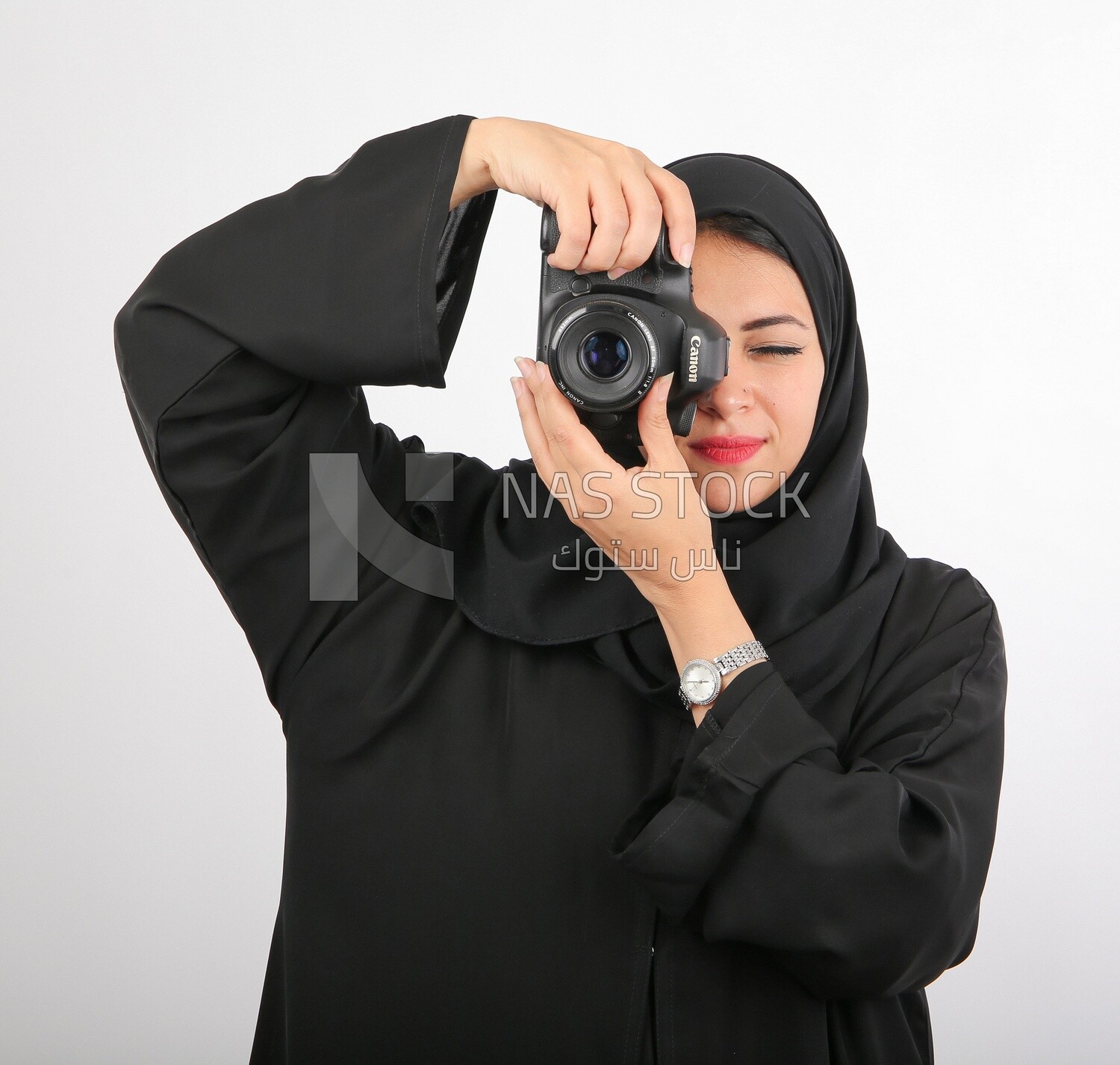 A woman with a hijab holding a camera