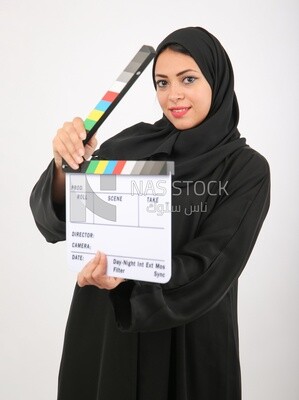 A woman with a hijab holding a clapperboard