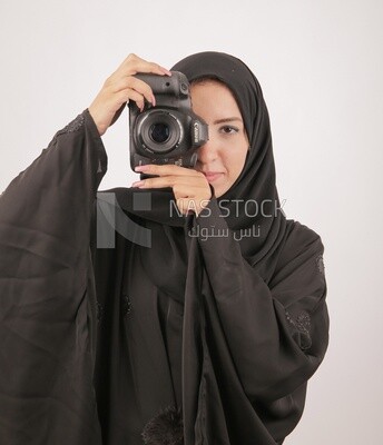 A woman with a hijab holding a camera