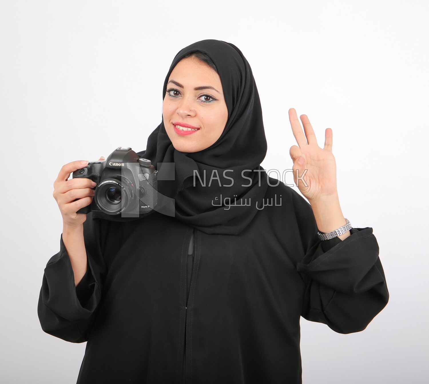 A woman with a hijab holding a camera