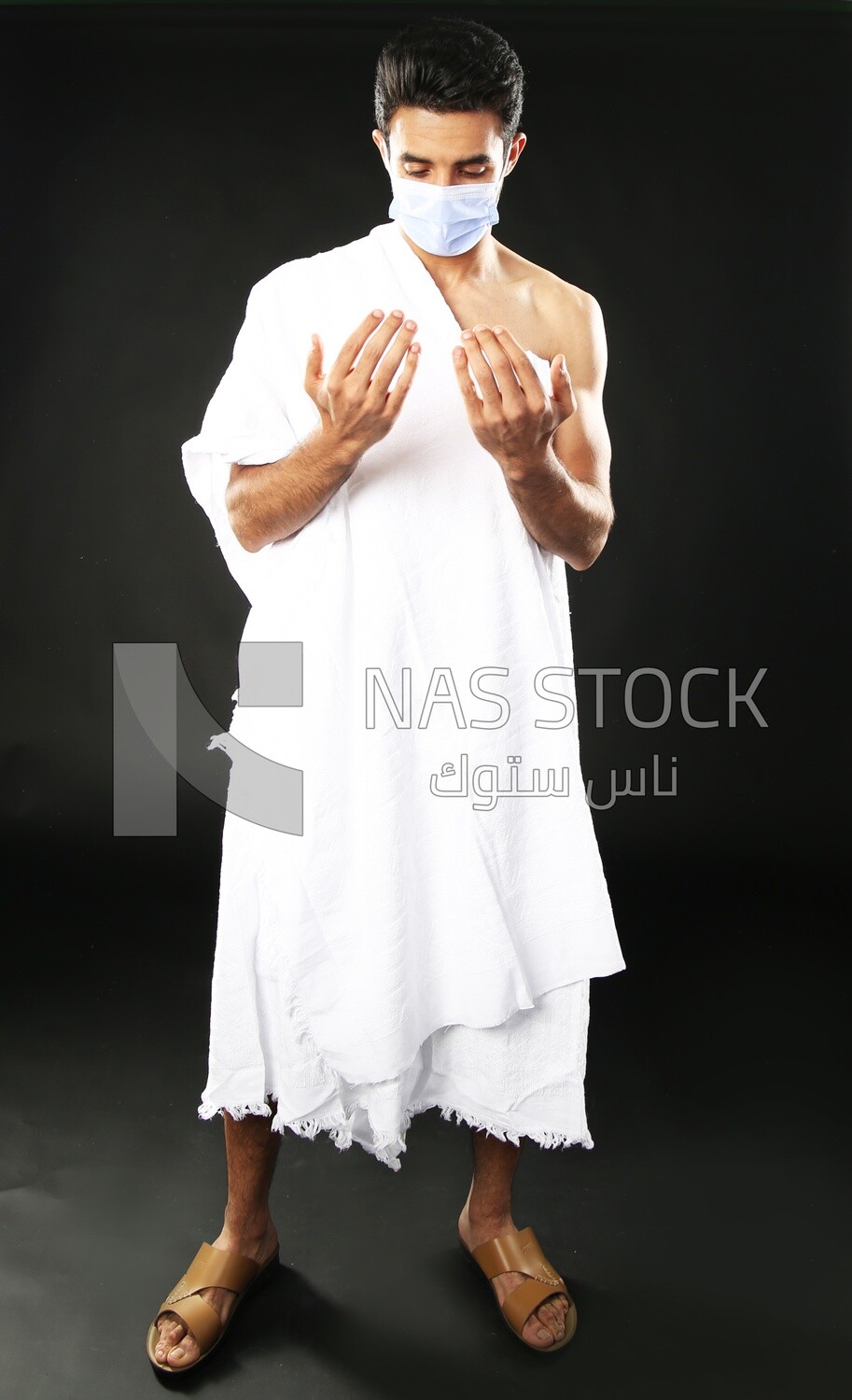A man wearing an ihram dress with a mask