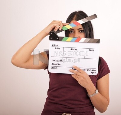 A woman holding a clapperboard on a white background ​