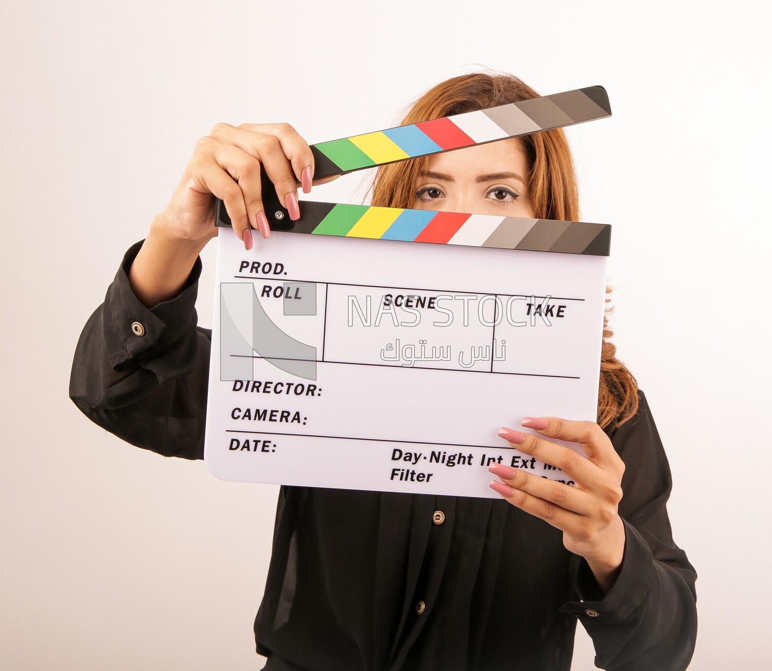 A woman holding a clapperboard on a white background ​