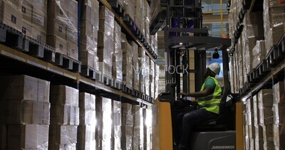 Worker stores and arranges boxes on warehouse shelves