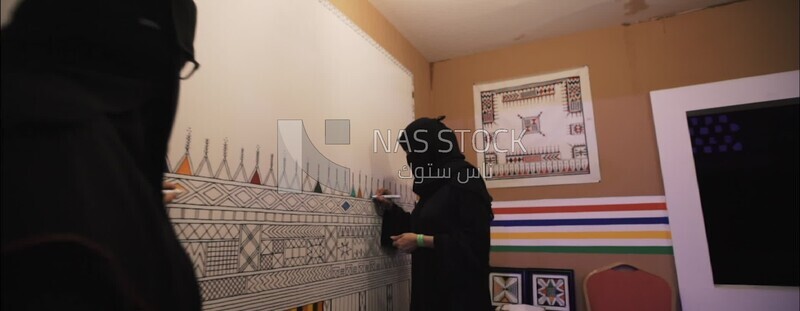 a saudi woman painting in the wall