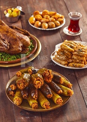 Side view of a scene from a Ramadan lunch table with roast duck, different types of stuffed vegetables and soup