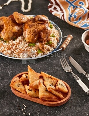 منظر جانبي لطاولة طعام مع طبق أرز بالدجاج و سمبوسة