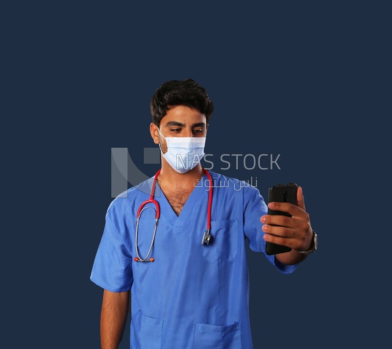 طبيب بكمامة يحمل هاتف محمول
