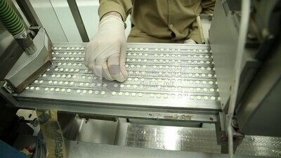 Doctor supervises the sorting and pressing of Medication tablets before packaging
