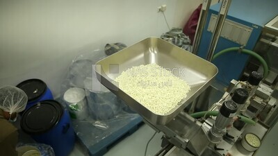 Specialist places the white medicine tablets in the nozzle of the machine to collect them in medicine strips.