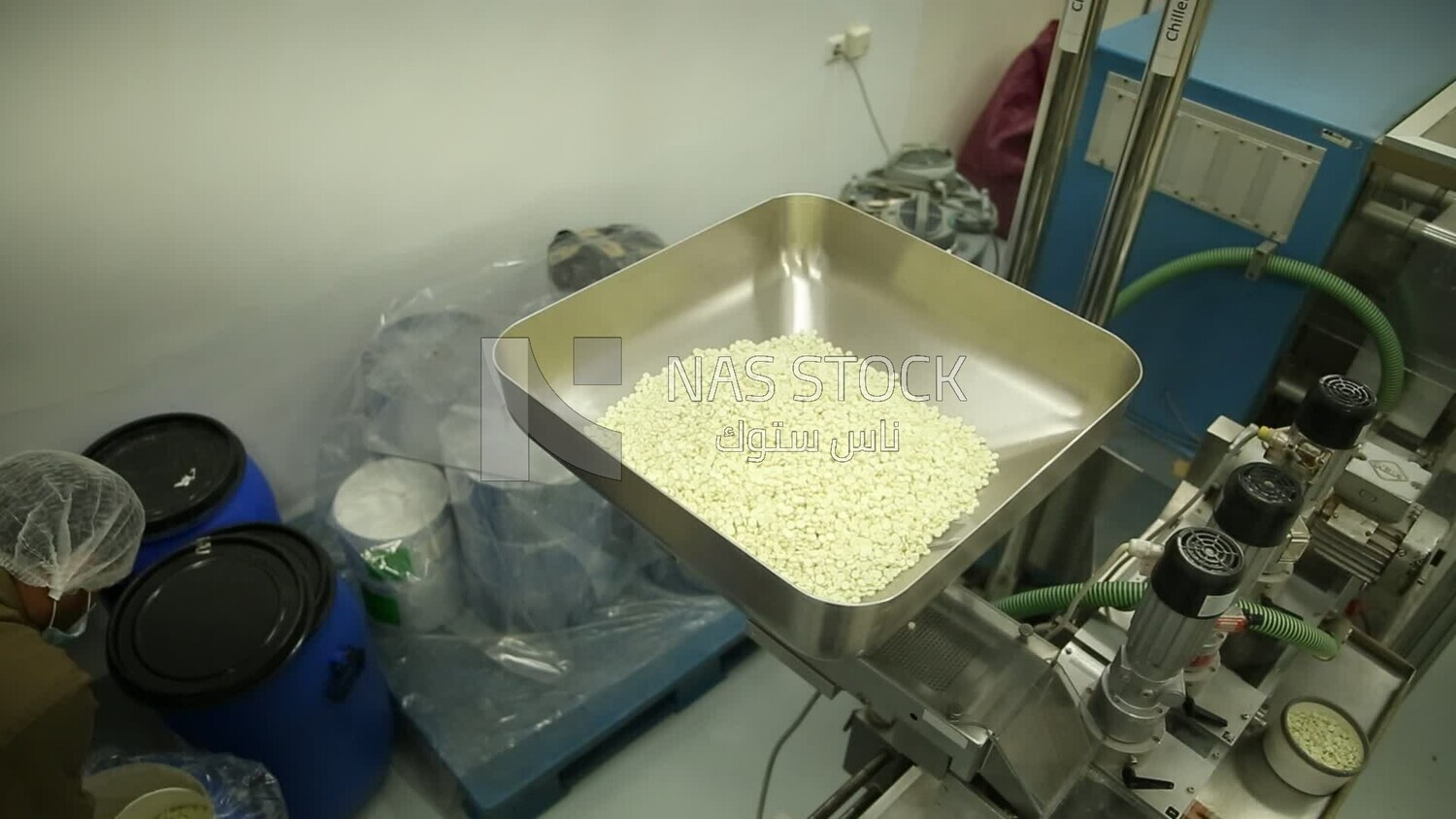 Specialist places the white medicine tablets in the nozzle of the machine to collect them in medicine strips.
