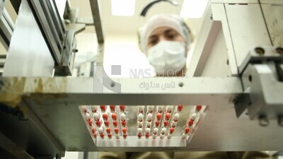 Doctor supervises the sorting and pressing of Medication tablets before packaging