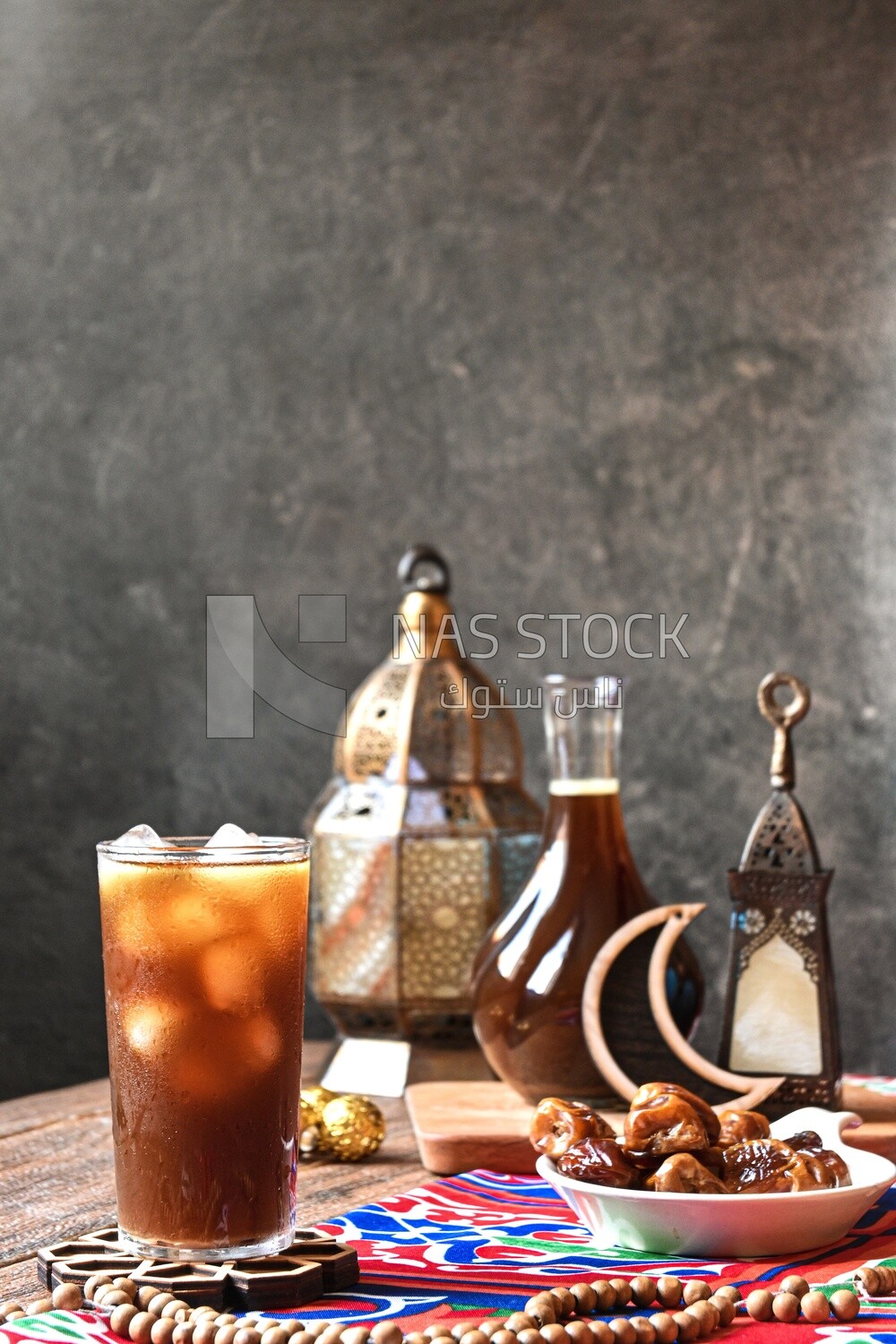 Cup of licorice juice with ice beside a plate of dates, ramadan juice
