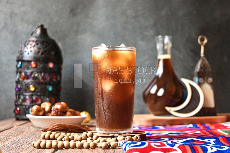 Cup of licorice juice with ice beside a plate of dates, ramadan juice
