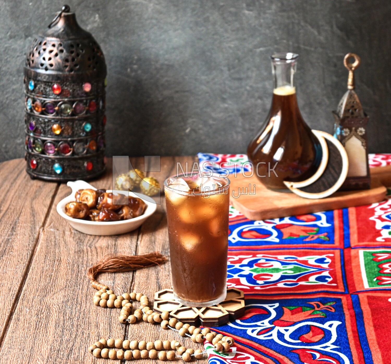 Cup of licorice juice with ice beside a plate of dates, ramadan juice