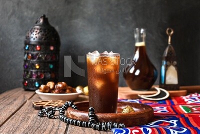 Cup of licorice juice with ice beside a plate of dates, ramadan juice