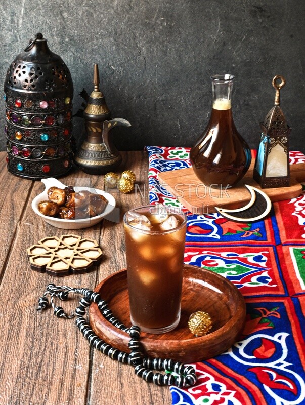 Cup of licorice juice with ice beside a plate of dates, ramadan juice