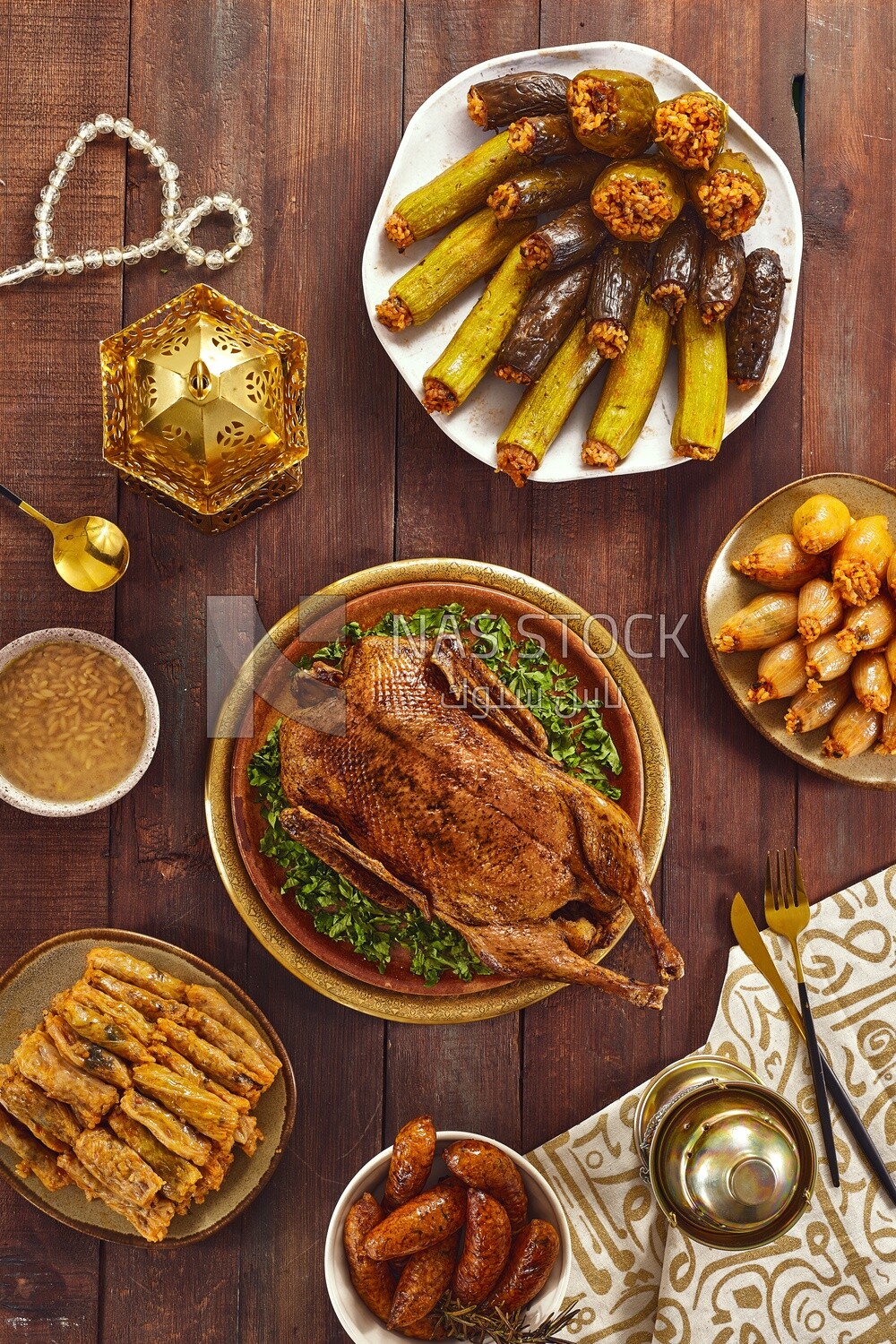 Top view of a scene from a Ramadan lunch table with roast duck, different types of stuffed vegetables and soup