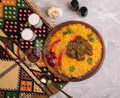 Wooden plate of delicious biryani rice with meat and two cups of milk and a plate of dates, traditional Arabic dishes, Arabic food, popular dishes, delicious recipes and dishes, delicious food