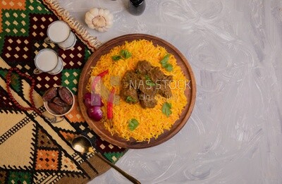 Wooden plate of delicious biryani rice with meat and two cups of milk and a plate of dates, traditional Arabic dishes, Arabic food, popular dishes, delicious recipes and dishes, delicious food