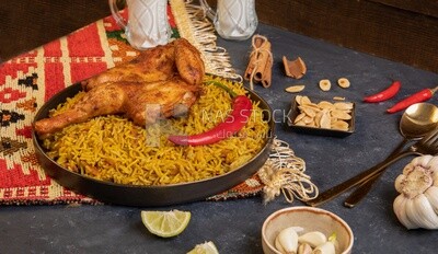 Plate of kabsa rice with chicken and cinnamon sticks, traditional Saudi food, Saudi restaurant, Saudi dishes