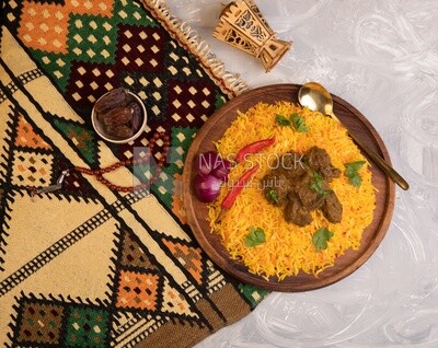 Wooden plate of delicious biryani rice with meat and a plate of dates,  traditional Arabic dishes, Arabic food, popular dishes, delicious recipes and dishes, delicious food