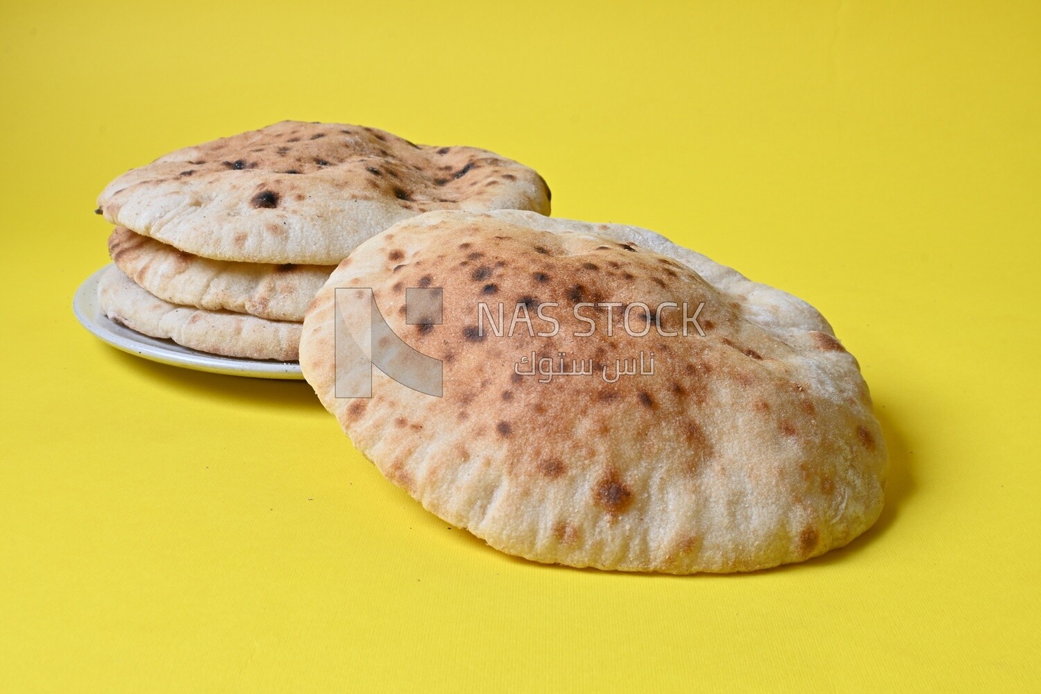 Arabic white bread, freshly baked, placed on a yellow background