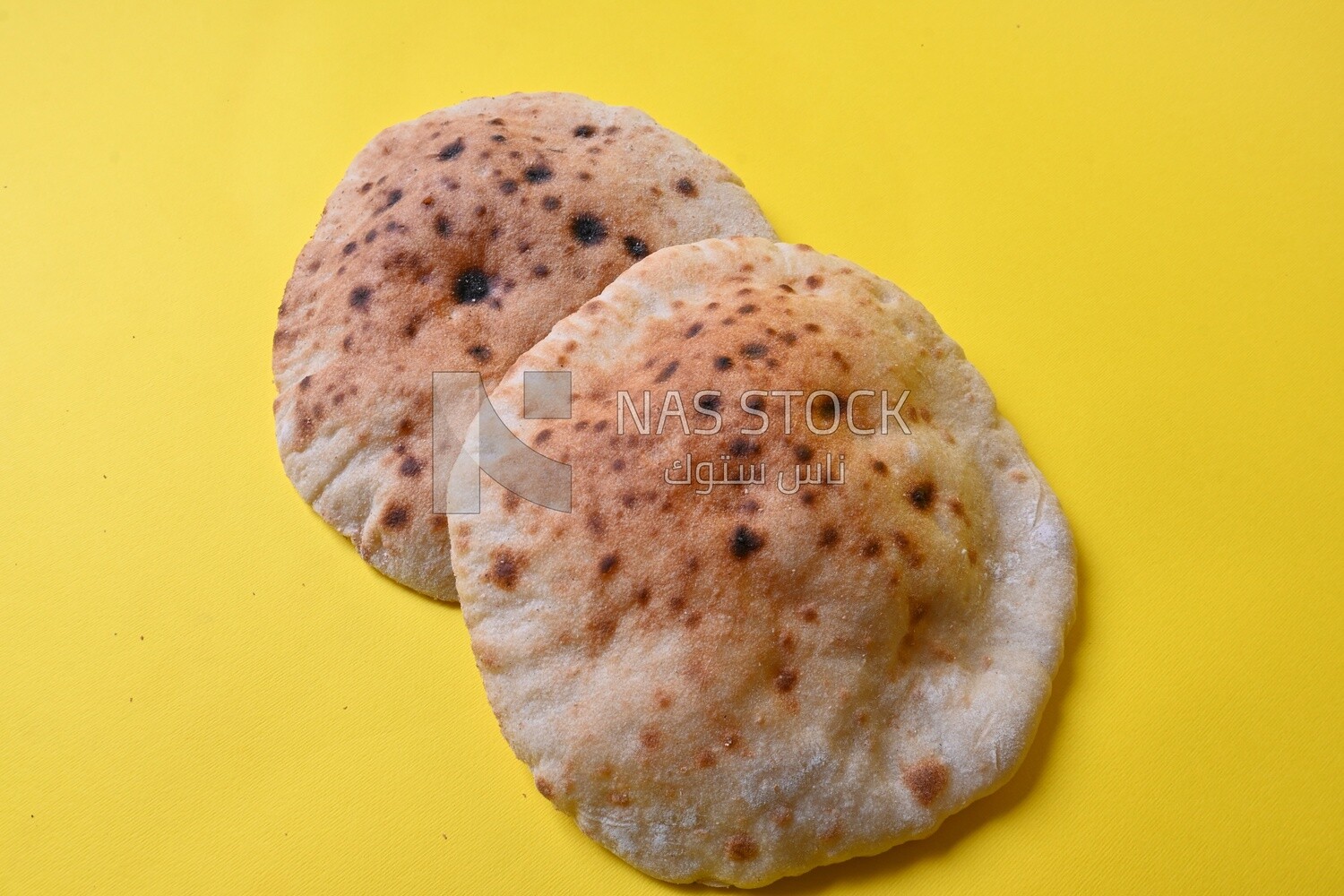 Arabic white bread, freshly baked, placed on a yellow background