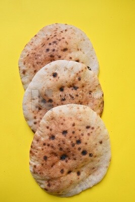 Arabic white bread, freshly baked, placed on a yellow background