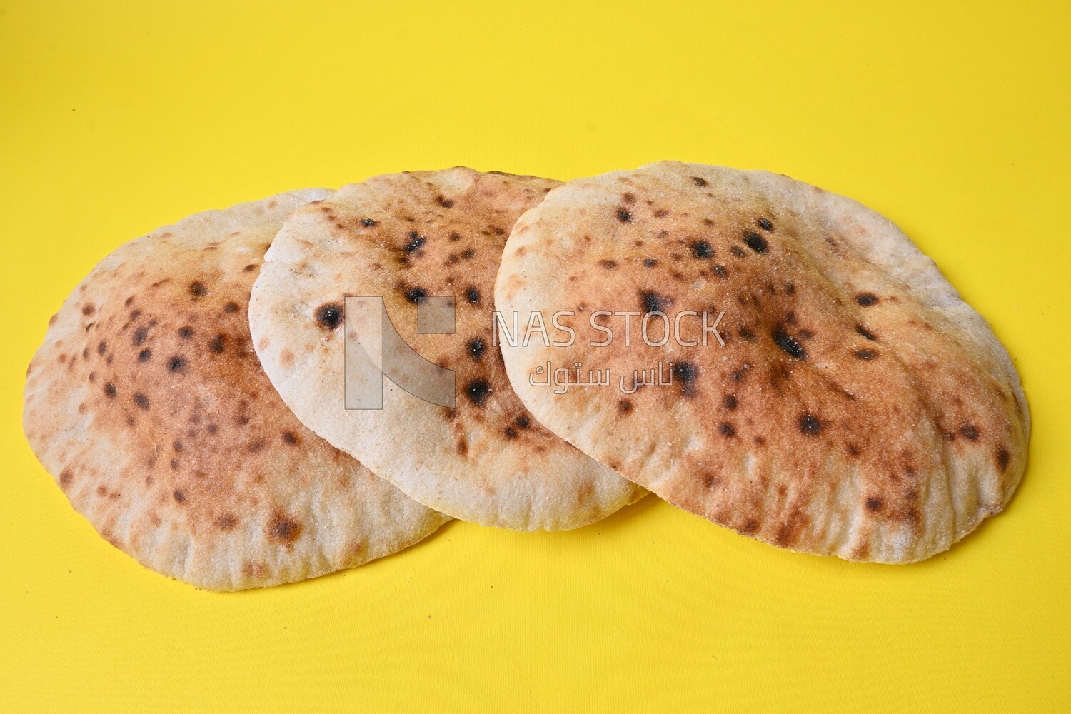 Arabic white bread, freshly baked, placed on a yellow background