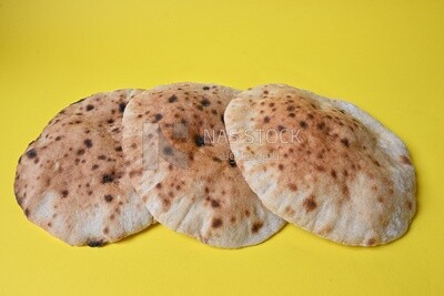 Arabic white bread, freshly baked, placed on a yellow background