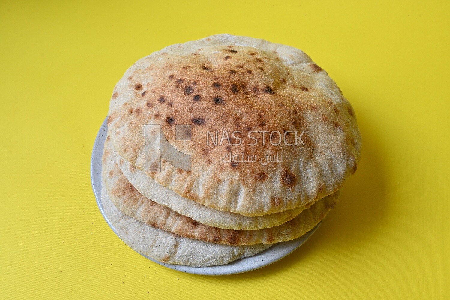 Arabic white bread, freshly baked, placed on a yellow background