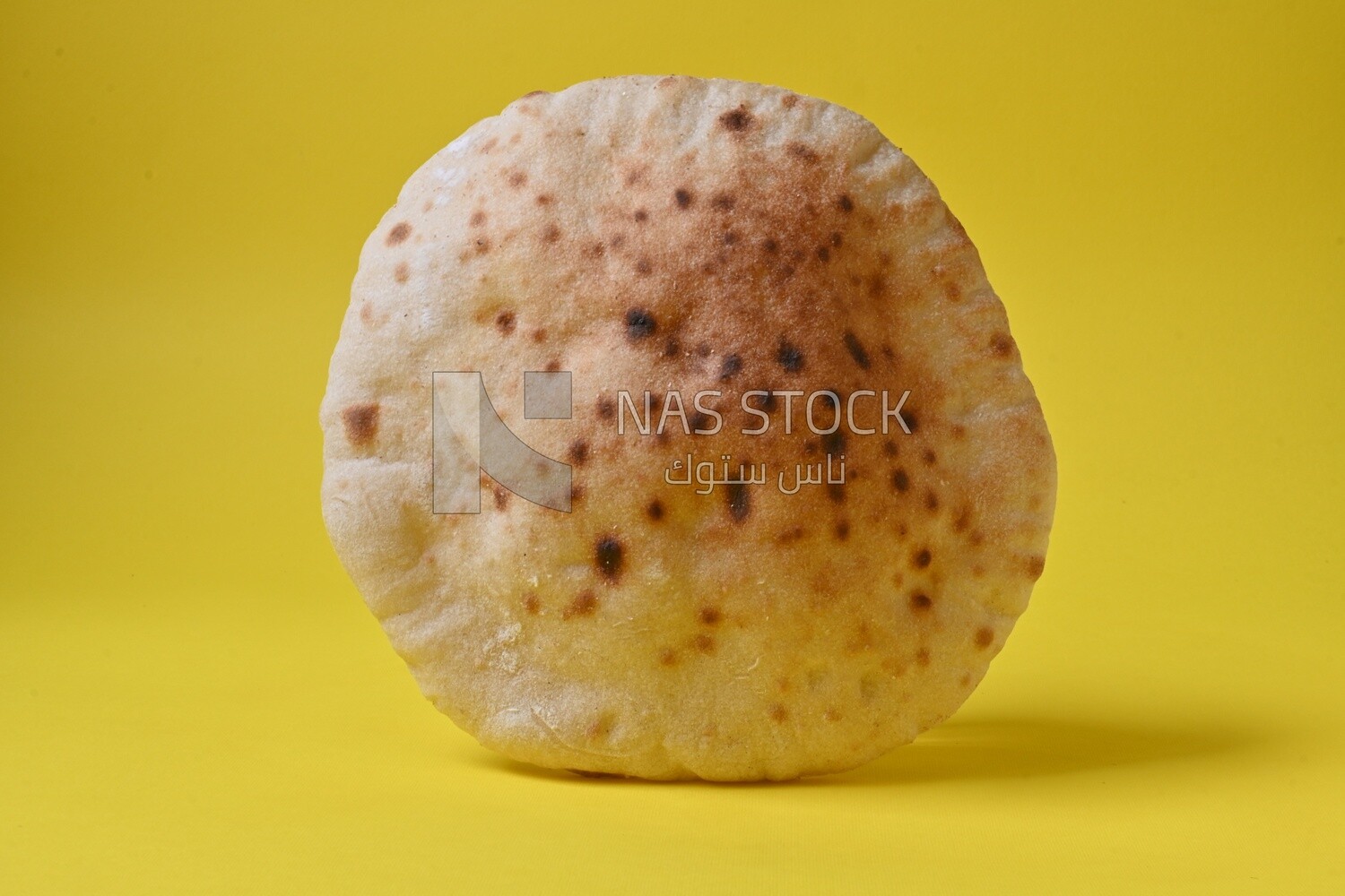 Arabic white bread, freshly baked, placed on a yellow background