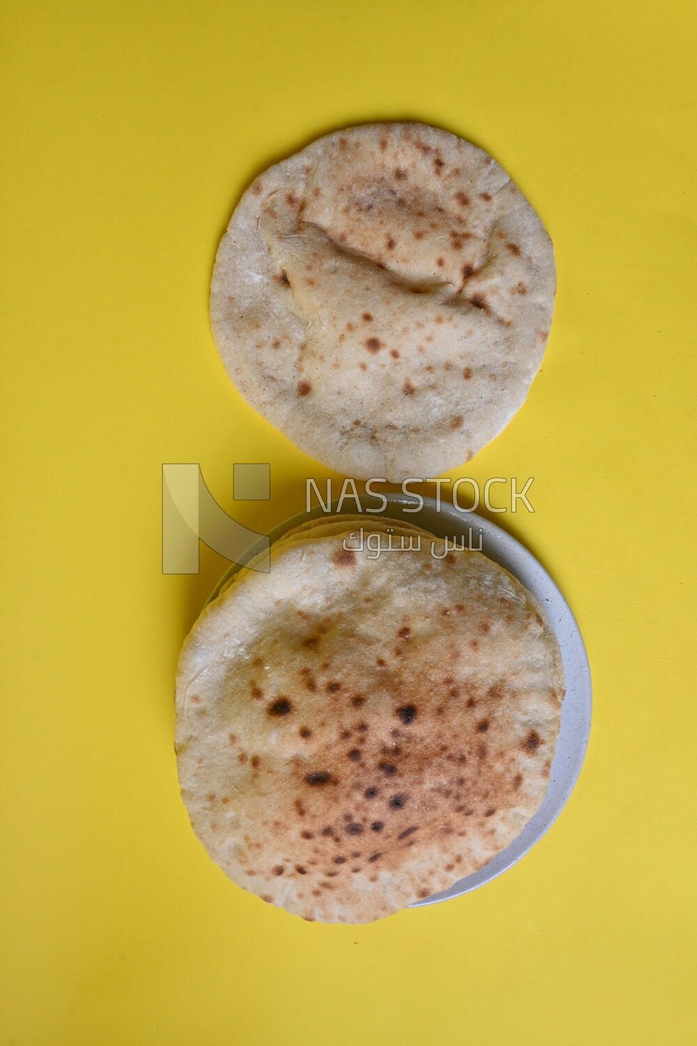 Arabic white bread, freshly baked, placed on a yellow background