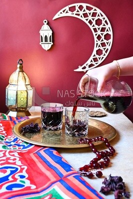 Hand holding jug of hibiscus pours into a cup, delicious juice