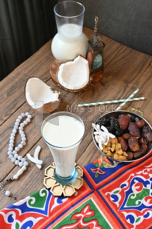 Cup of sobia beside a coconut with a plate of dried fruits(khoshaf), delicious dessert, Ramadan juice, delicious juice, traditional juice
