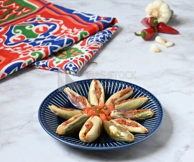 Plate of Pickled eggplant with sauce in it beside garlic and red pepper, Egyptian pickles, Arabic restaurants