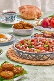 close-up of a dish of foul medames with vegetables, falafel tablets, a plate of fried egg, Arabic breakfast, oriental breakfast, arab restaurant